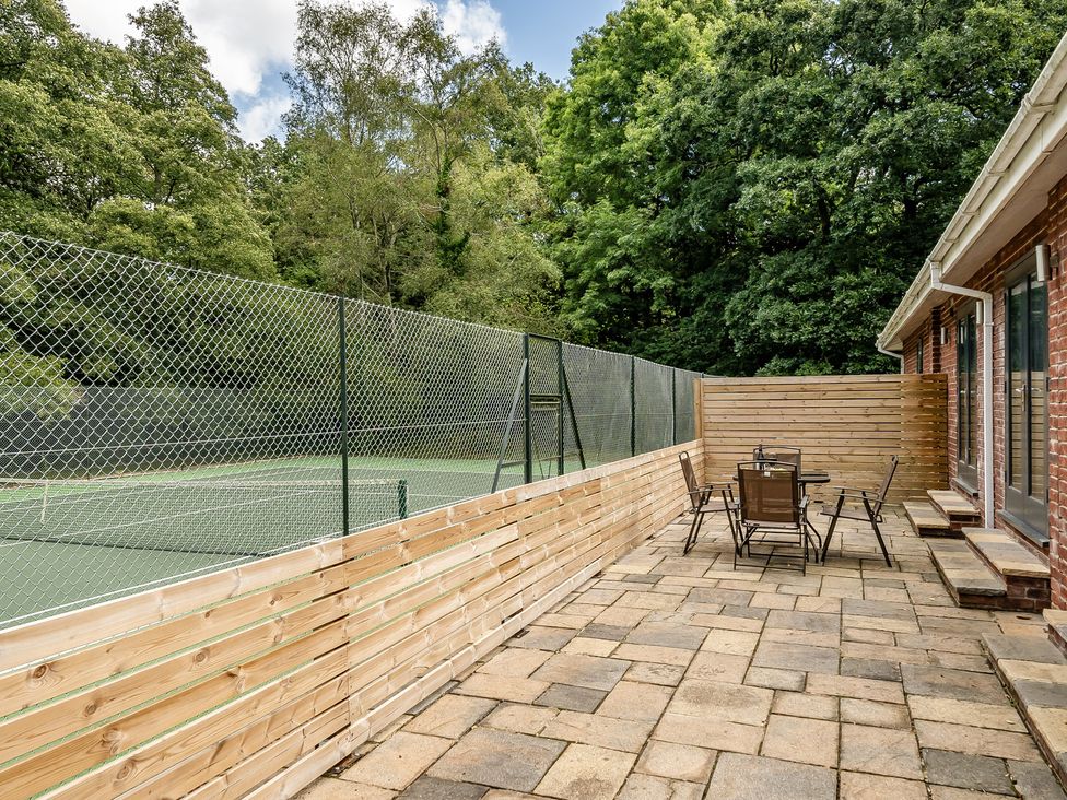An outdoor area with a tennis court and a seating area at The Annex in Wimborne Minster
