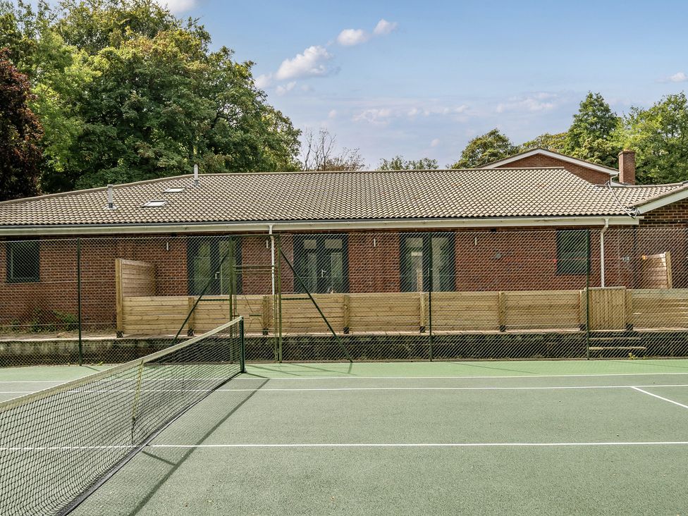 A tennis court with a building in the background at The Annex in Wimborne Minster