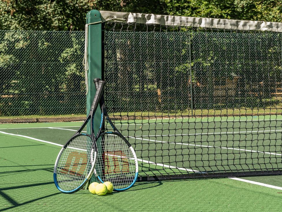 Two tennis rackets and three tennis balls on a tennis court at The Annex Wimborne Minster
