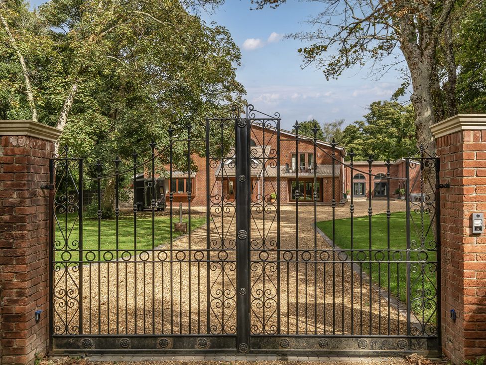 A gated entrance with a gravel driveway and a house in the background at The Annex in Wimborne Minster