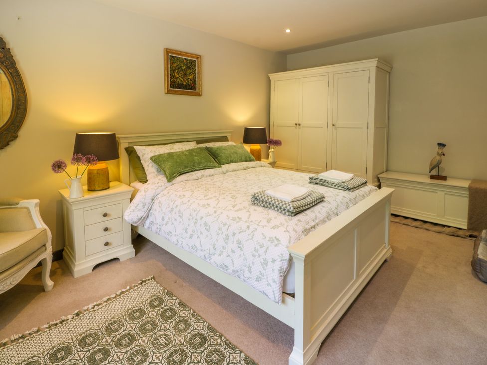 A bedroom with a bed and nightstand at Nithbank Cottage