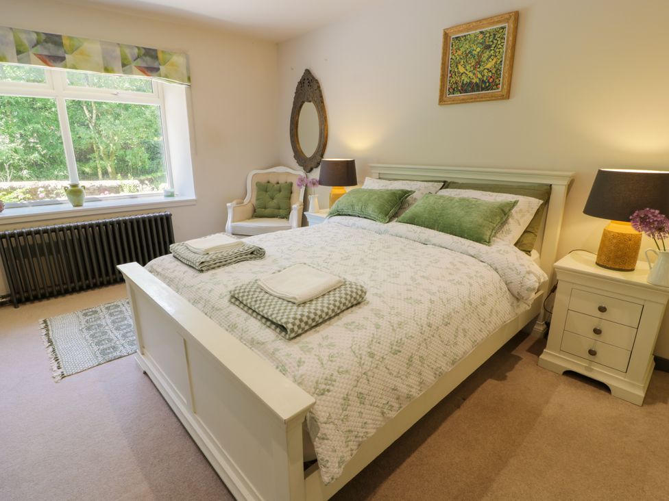 A bedroom with a bed and bedside table at Nithbank Cottage