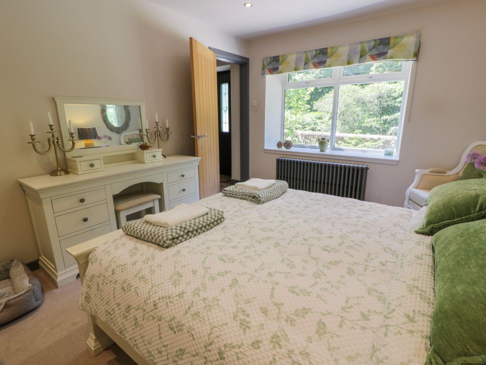 A bedroom with a bed and dresser at Nithbank Cottage