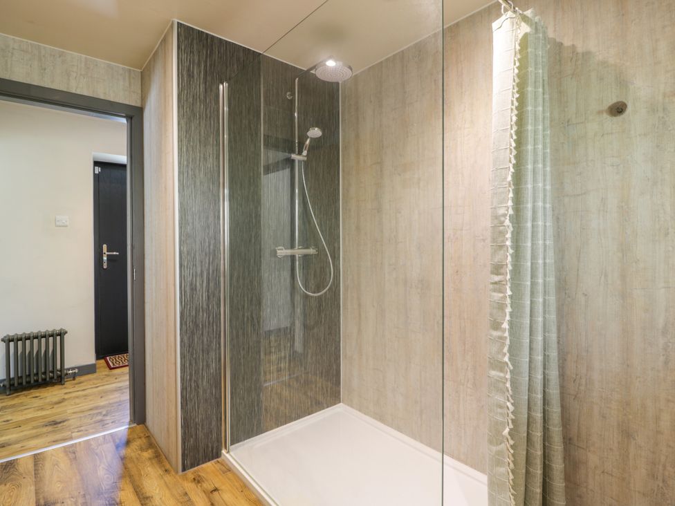 A shower with a curtain and a radiator at Nithbank Cottage