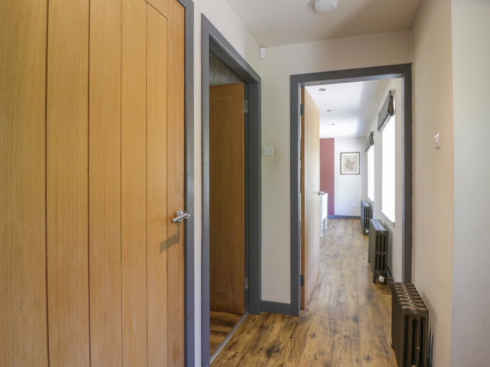 A hallway with wooden doors and flooring at Nithbank Cottage