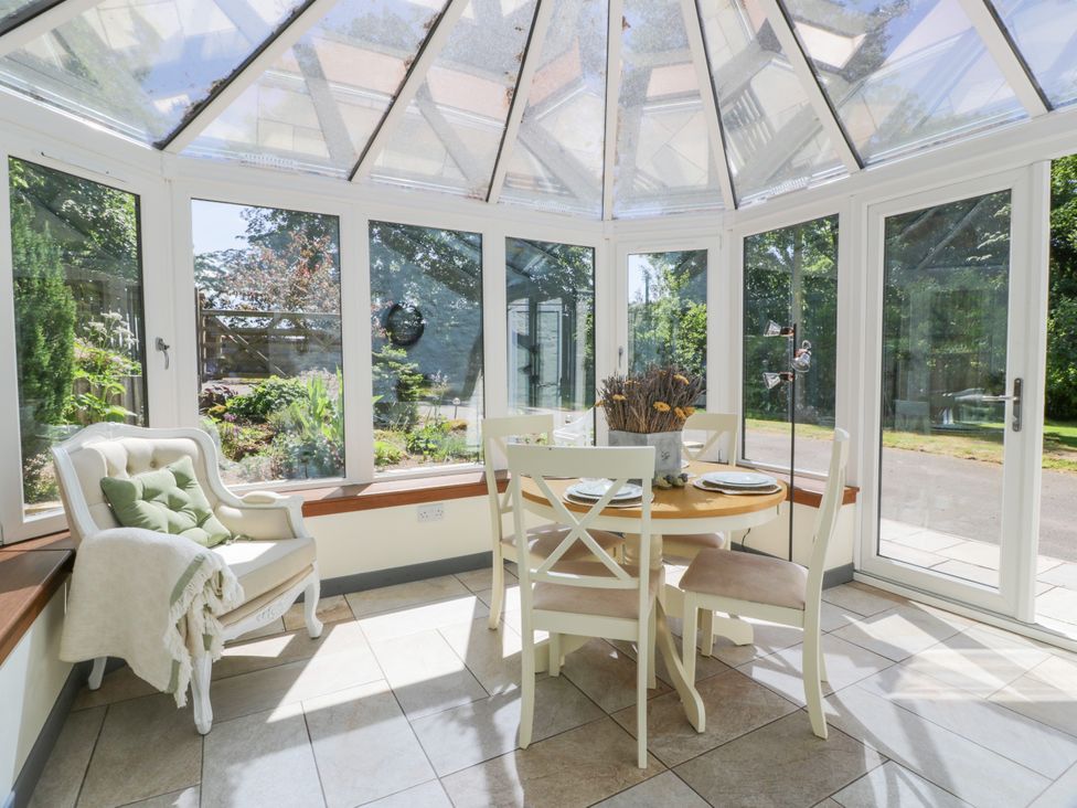 A conservatory with a dining table and chairs at Nithbank Cottage