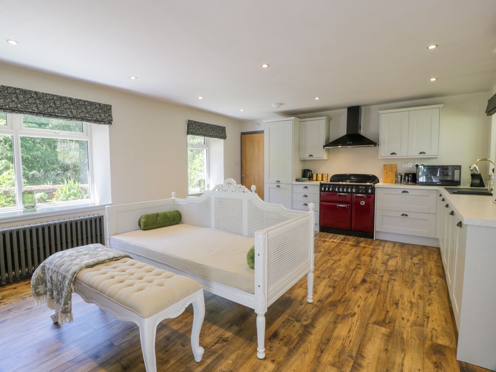 A kitchen with a red stove and white cabinets at Nithbank Cottage 
