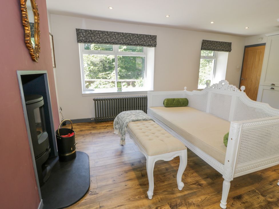 A living room with a couch, bench, and fireplace at Nithbank Cottage
