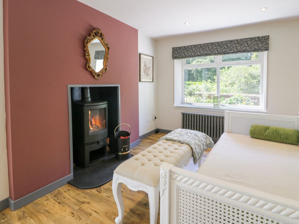 A bedroom with a fireplace and bench at Nithbank Cottage