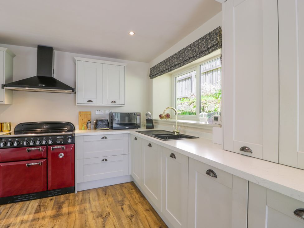 A kitchen with cabinets, oven, sink, and microwave at Nithbank Cottage