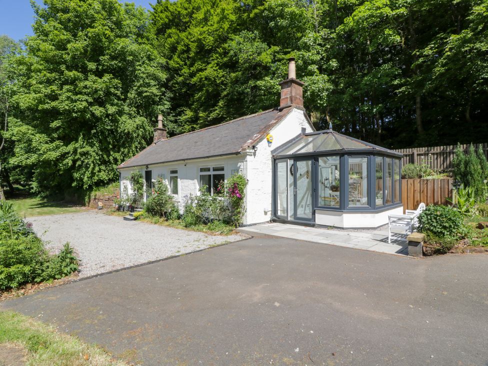 A cottage with a conservatory and parking area at Nithbank Cottage in 