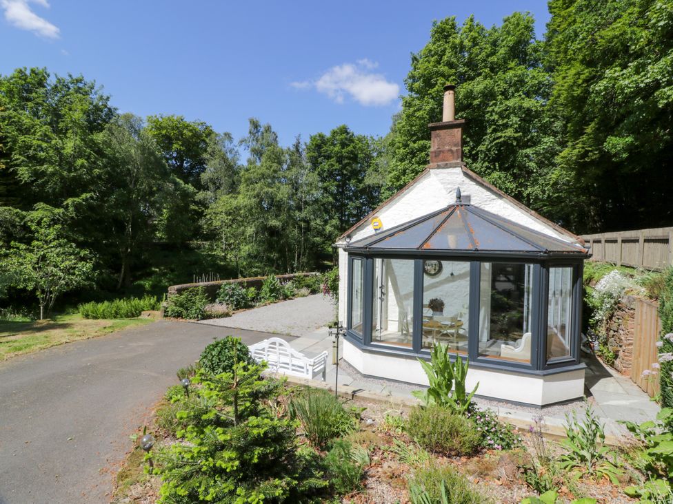A cottage with a conservatory and garden at Nithbank Cottage