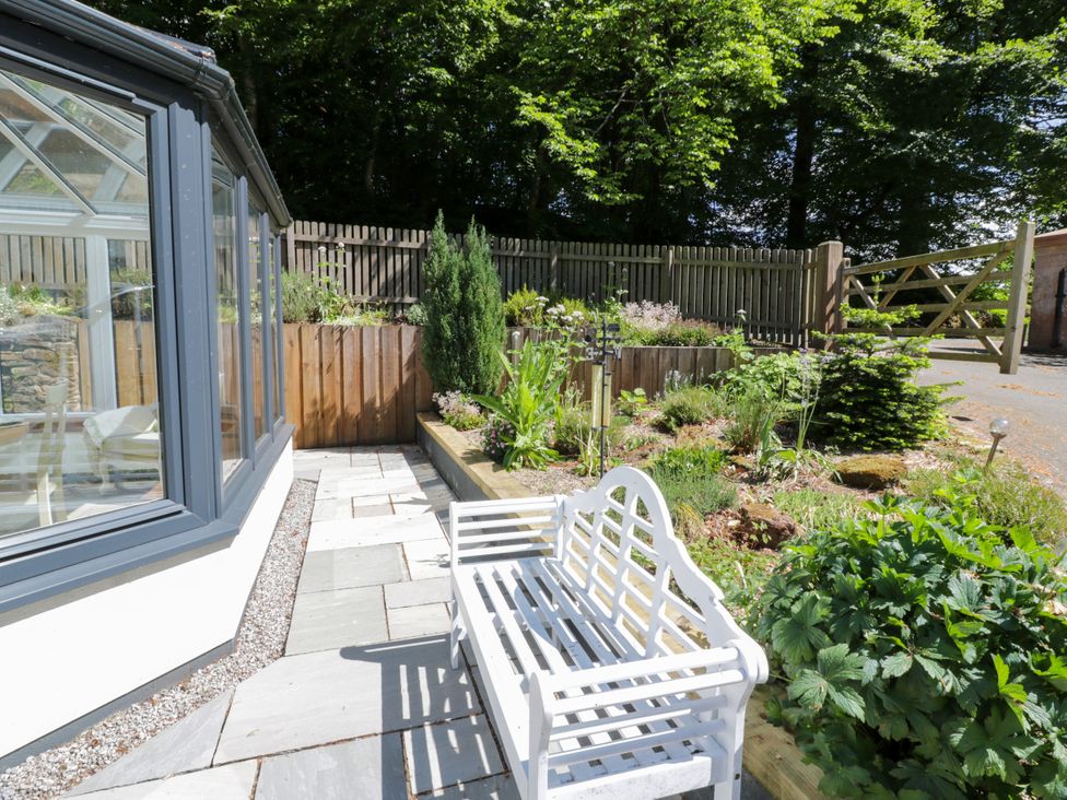 A garden with a bench and plants at Nithbank Cottage