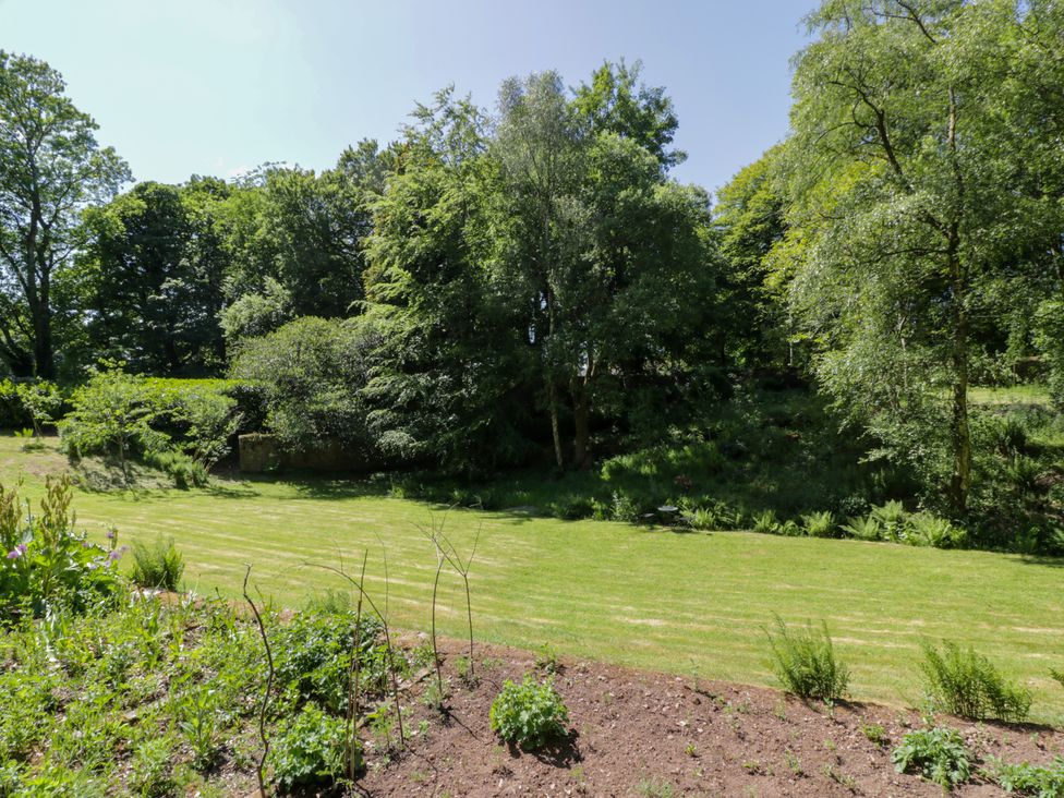 A garden with grass and trees at Nithbank Cottage