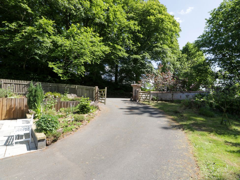 A gravel road with a gate and trees at Nithbank Cottage