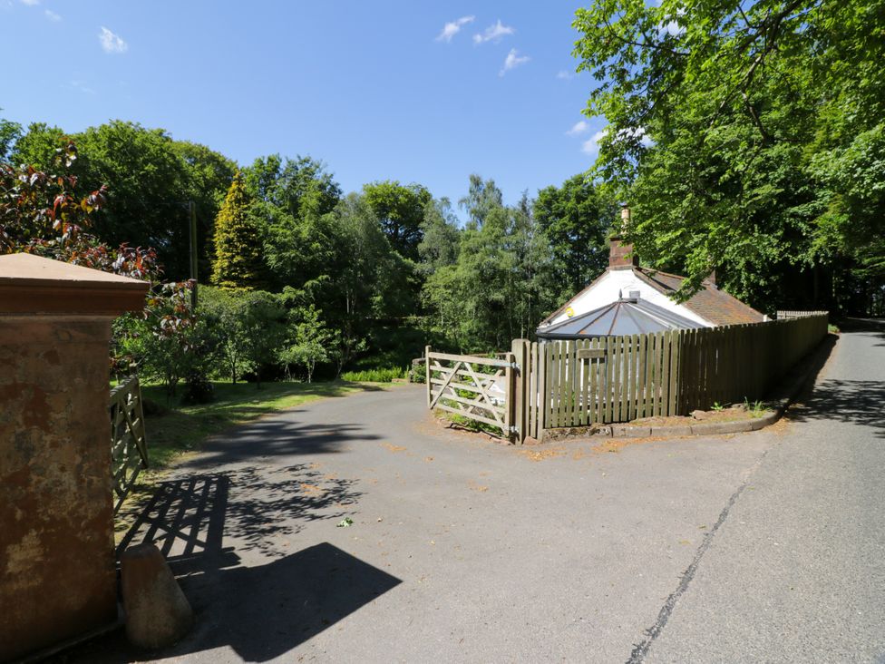A cottage with a wooden fence by the road at Nithbank Cottage