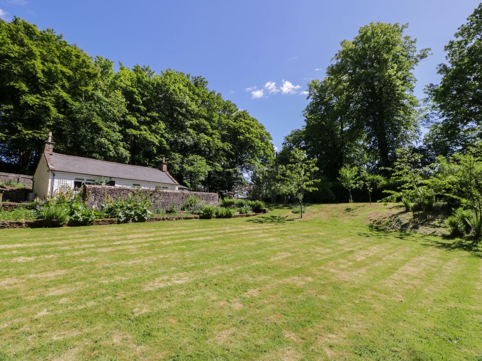 A garden with a cottage and trees at Nithbank Cottage in 