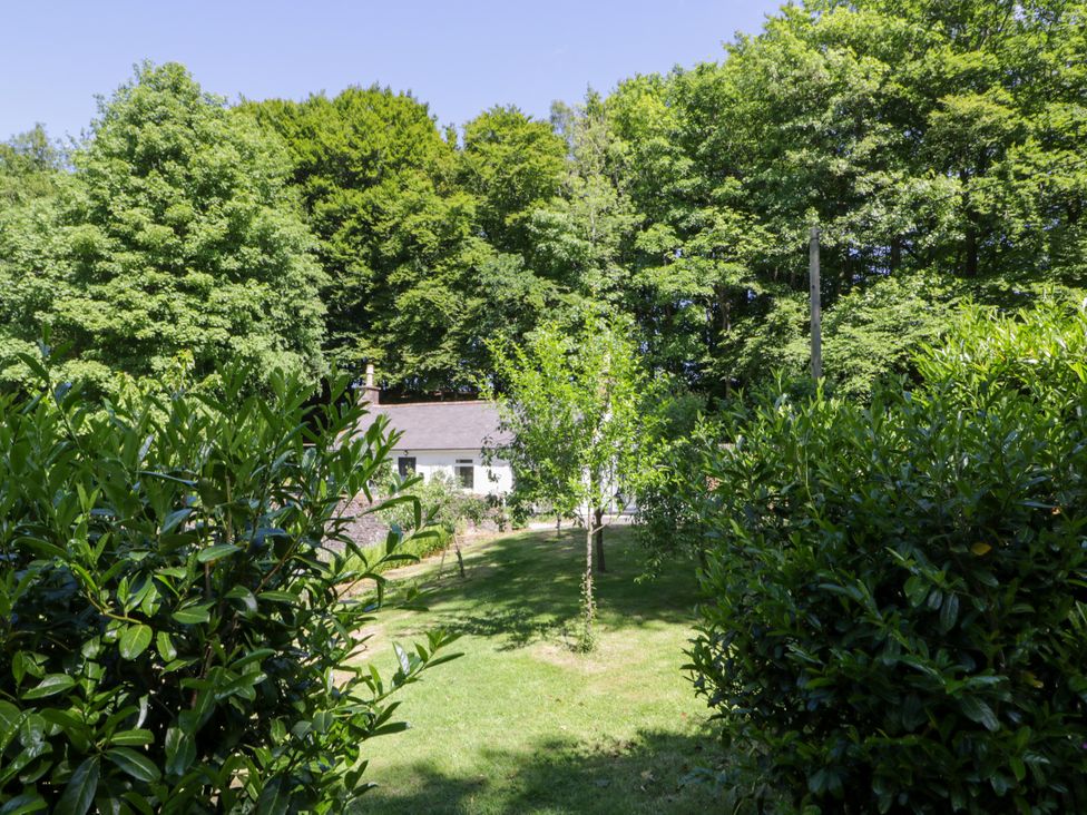A garden with trees and a house at Nithbank Cottage in 