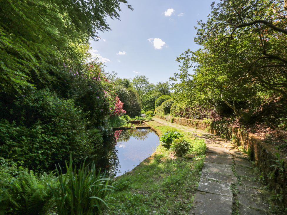 A garden with a pond and a pathway at Nithbank Cottage