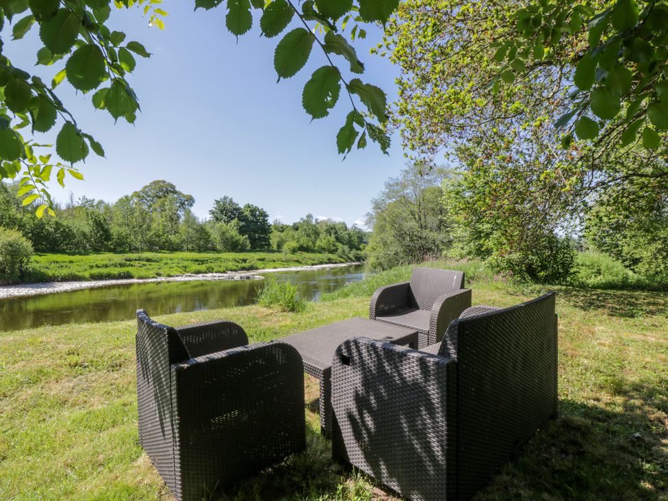 An outdoor seating area by a river at Nithbank Cottage