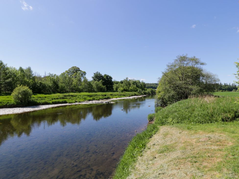 A river surrounded by grass and trees at Nithbank Cottage