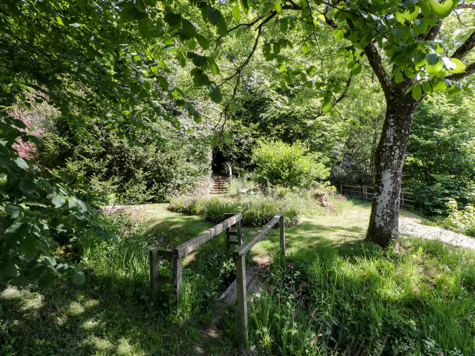 A garden with trees and a path leading to stairs at Nithbank Cottage in 