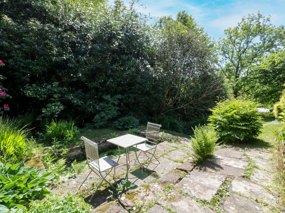 A garden with a table and chairs on a stone patio at Nithbank Cottage