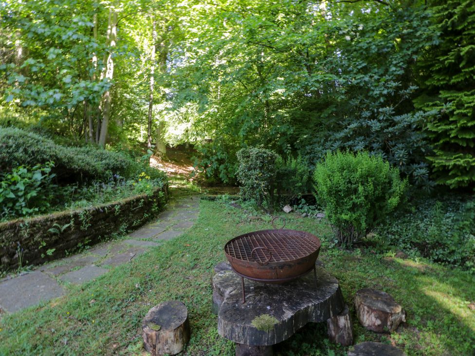 A garden with a grill on a wooden stand at Nithbank Cottage