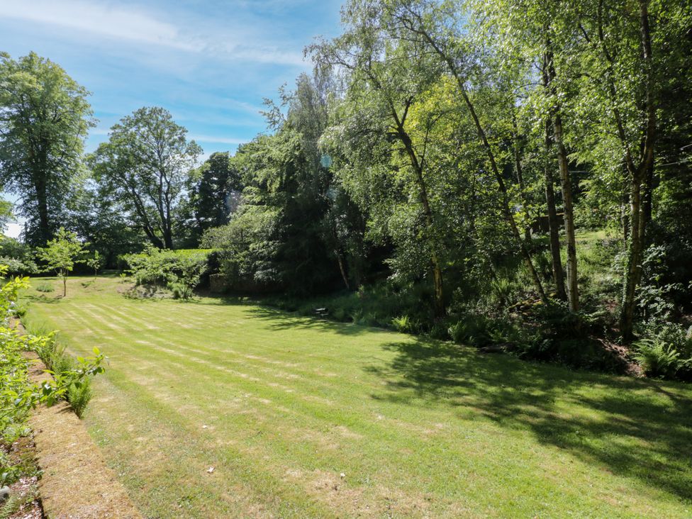 A garden with grass and trees at Nithbank Cottage in 
