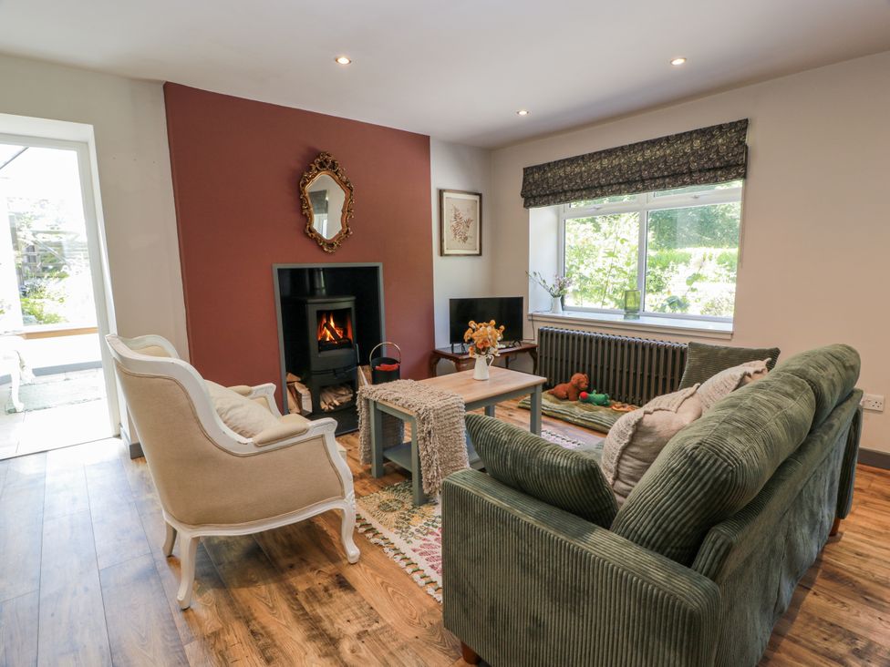 A living room with furniture and a fireplace at Nithbank Cottage Thornhill