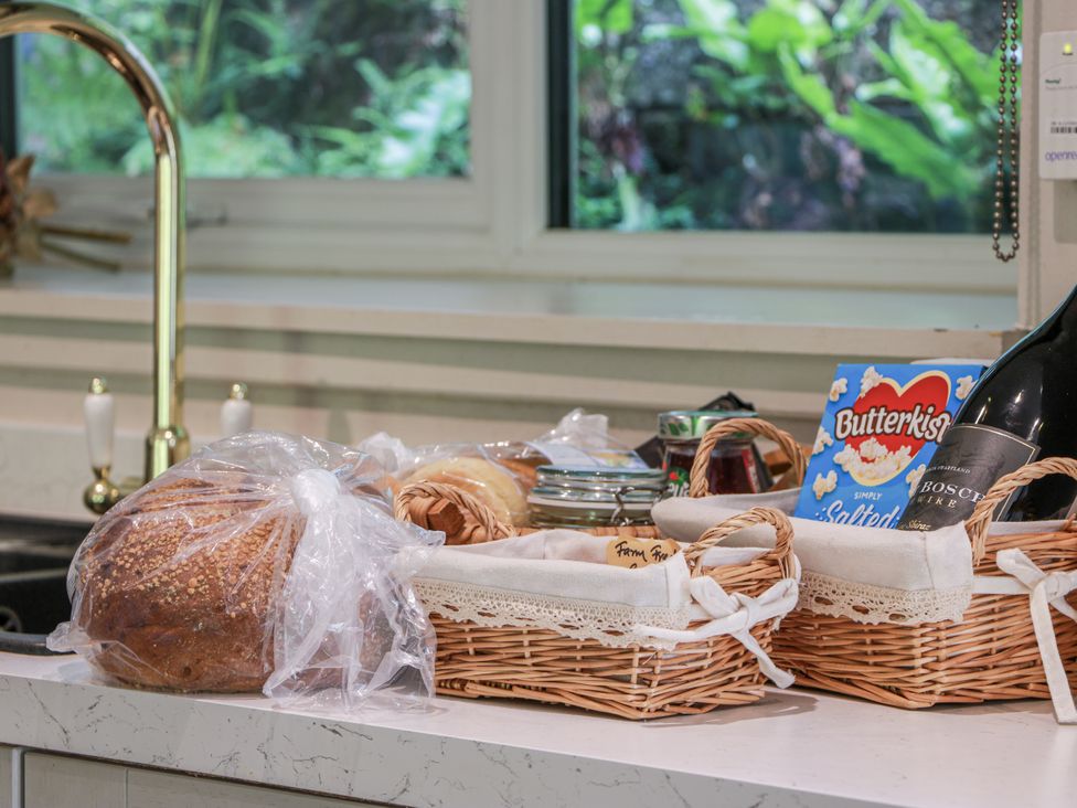 A kitchen countertop with bread, baskets, popcorn, and wine at Nithbank Cottage Thornhill