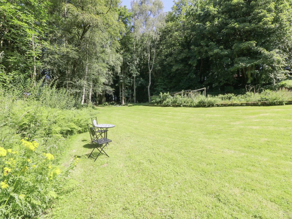 A garden with a table and chair at Nithbank Cottage Thornhill