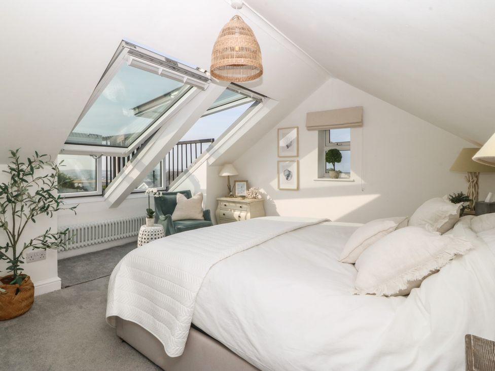 A bedroom with a bed and windows at Trem Ynys in Mynytho near Abersoch