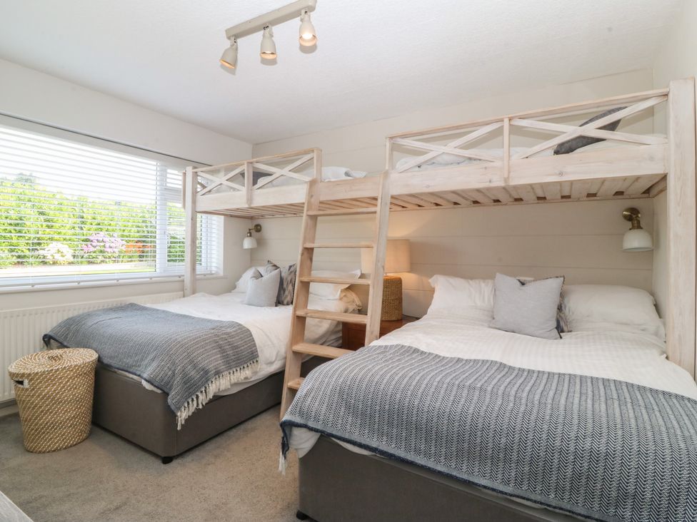 A bedroom with bunk beds and a double bed at Trem Ynys in Mynytho near Abersoch