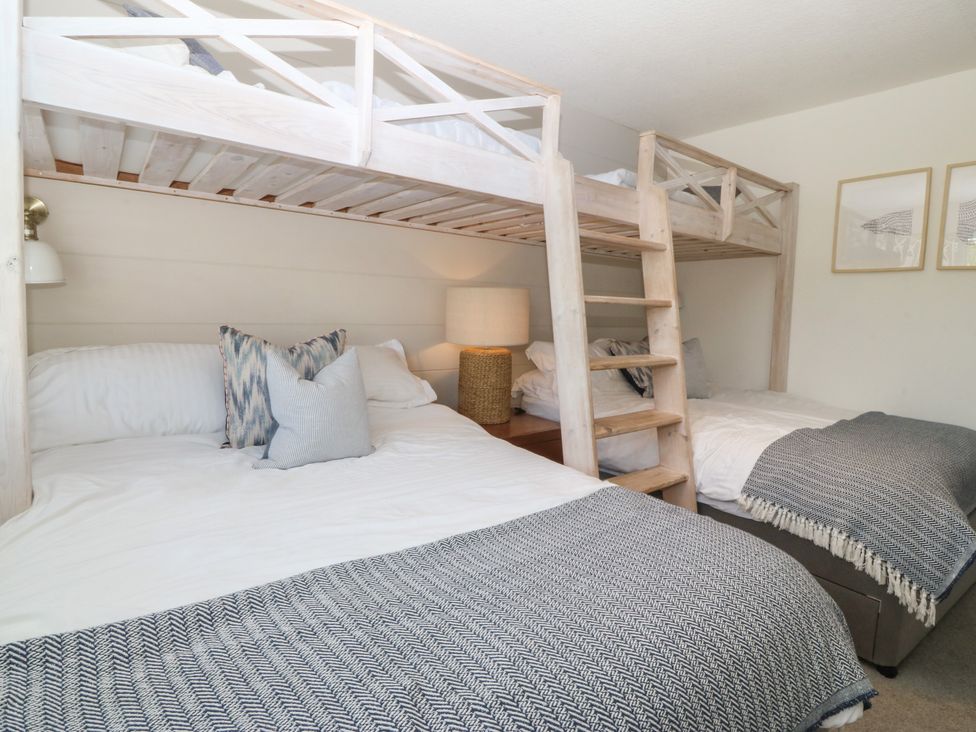 A bedroom with a bunk bed and a double bed at Trem Ynys near Abersoch