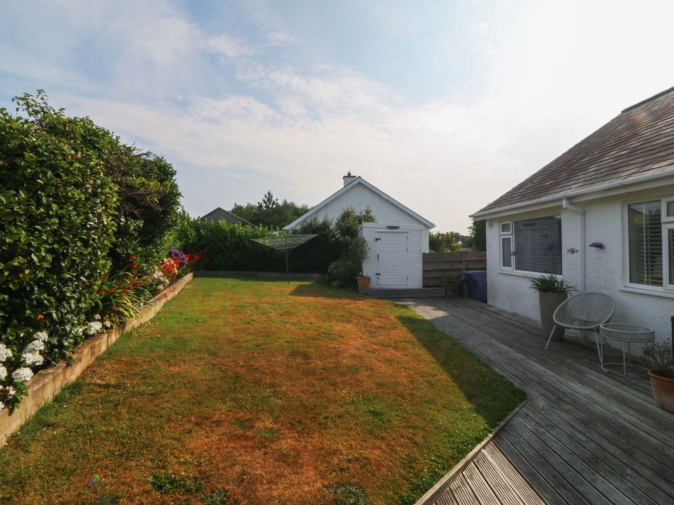 A garden with wooden decking and flower beds at Trem Ynys near Abersoch