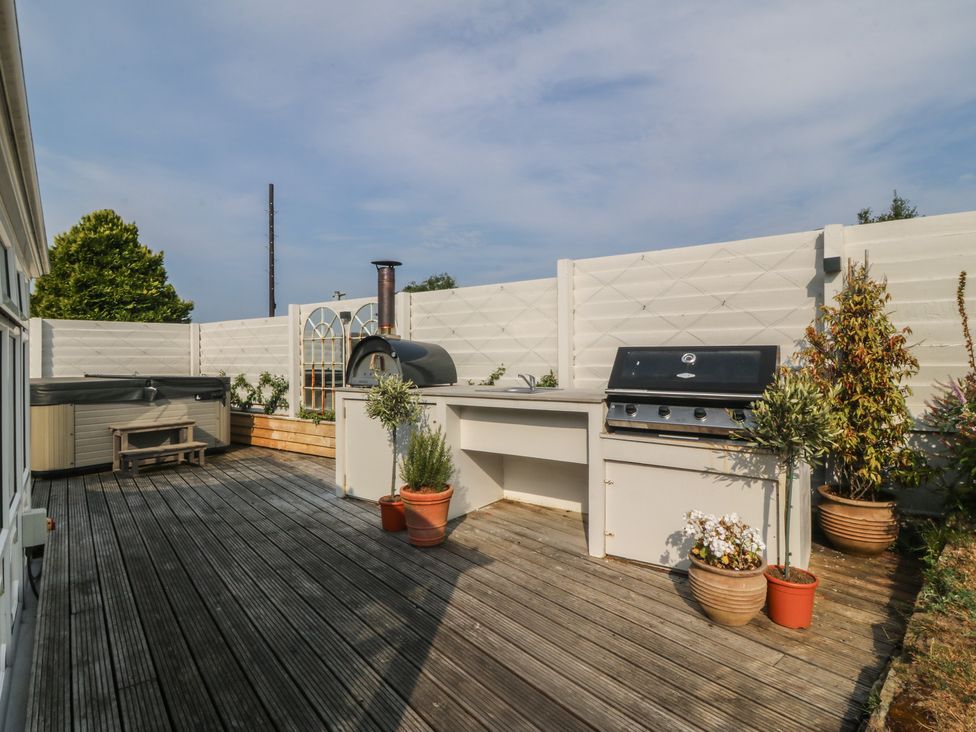 An outdoor patio with a grill and pizza oven at Trem Ynys near Abersoch