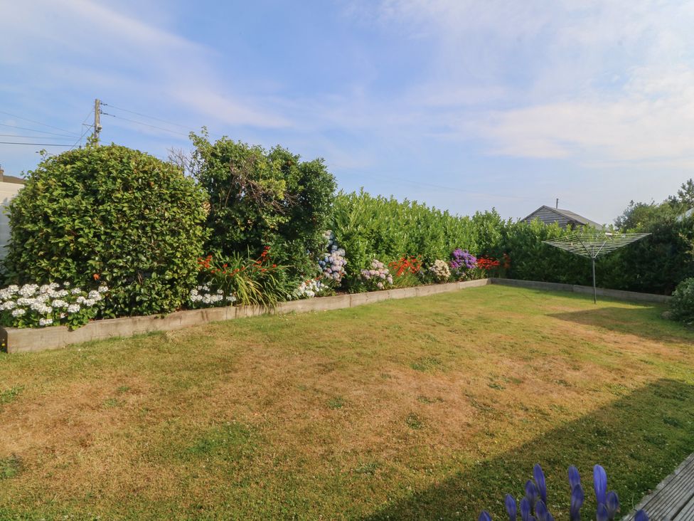 A garden with grass and flower beds at Trem Ynys in Mynytho near Abersoch