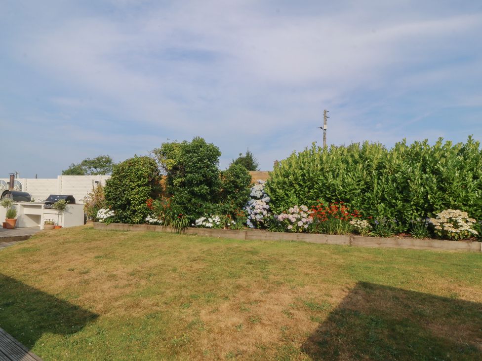 A garden with flowers and a barbecue at Trem Ynys near Abersoch