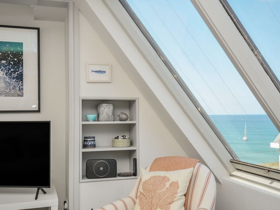 A living room with a television and shelf at The Lookout in Polzeath