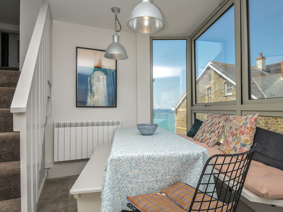 A dining room with a table and cushions at The Lookout in Polzeath