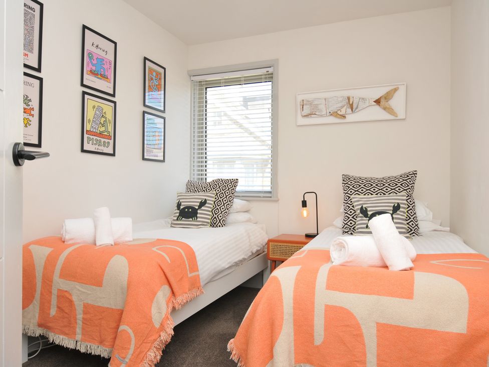 A bedroom with two beds and wall art at The Lookout in Polzeath