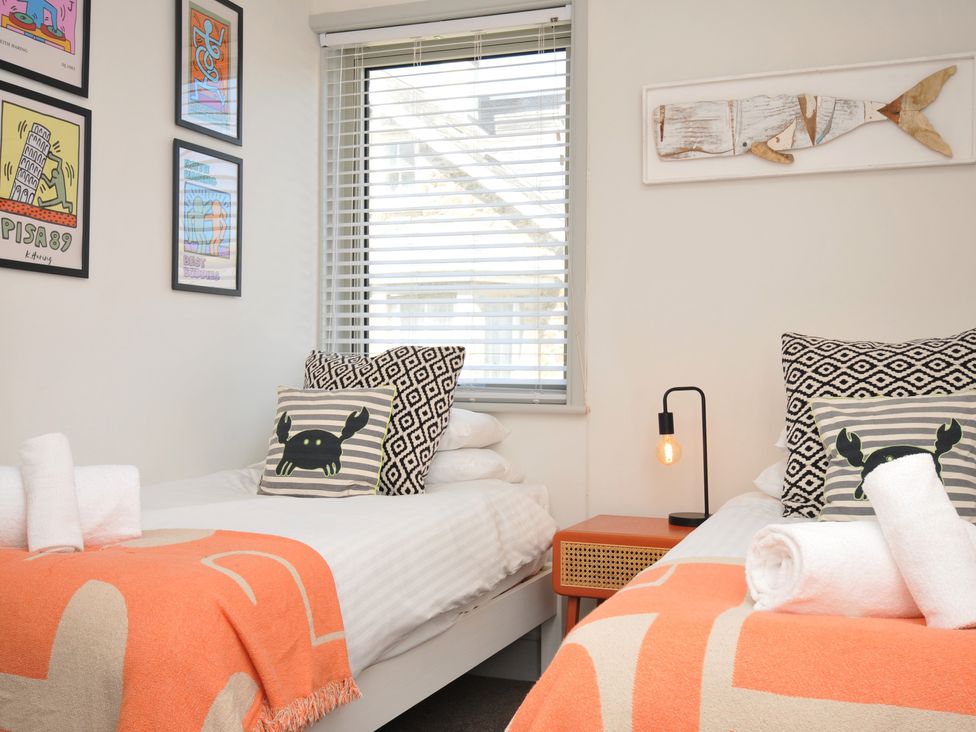 A bedroom with two beds and artwork on the walls at The Lookout Polzeath