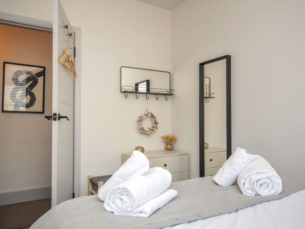 A bedroom with towels on the bed and a mirror at The Lookout in Polzeath