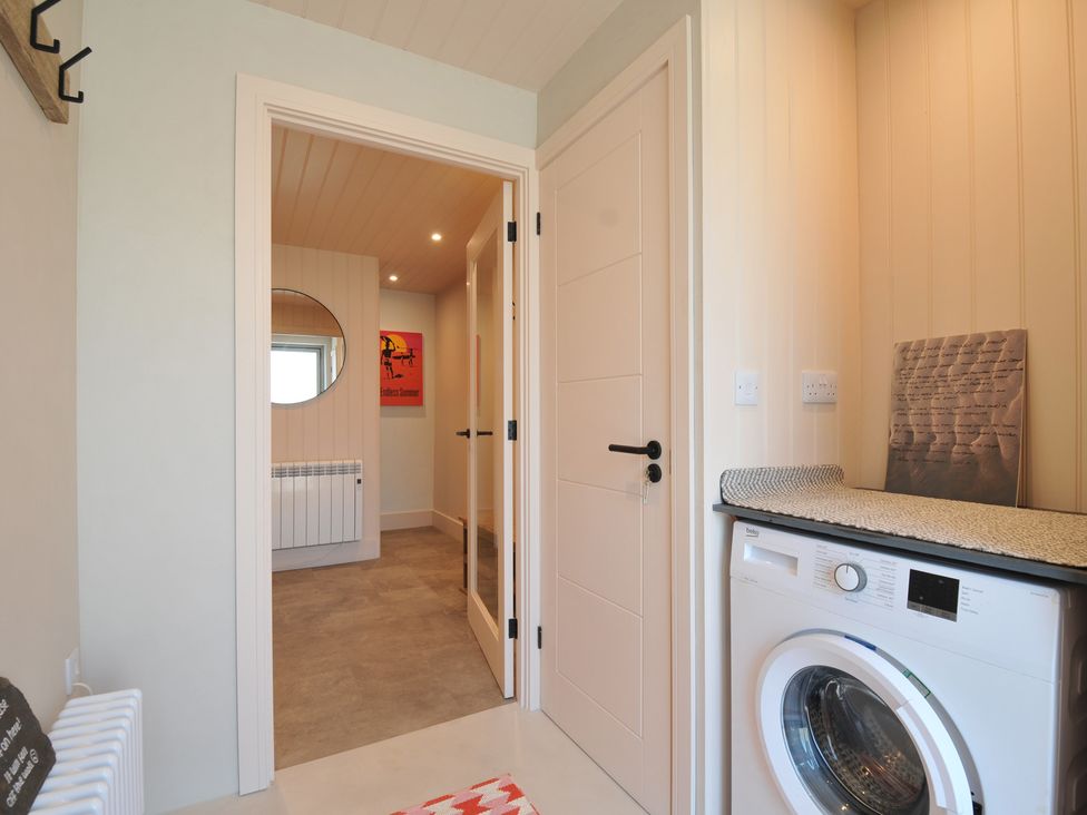 A laundry room with a washing machine and a mirror at The Lookout in Polzeath
