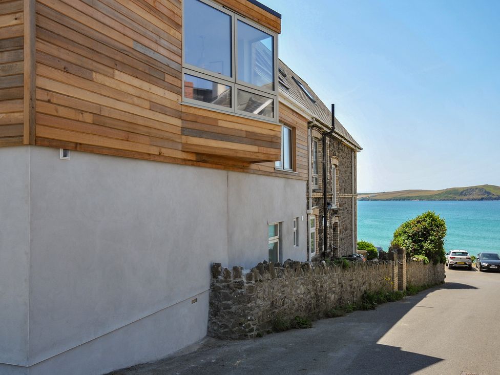 A view of a building facade with water in the background at The Lookout Polzeath