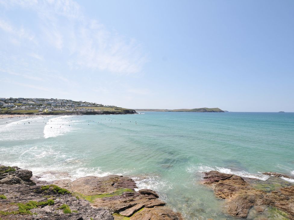 A beach with waves and surfers at The Lookout in Polzeath