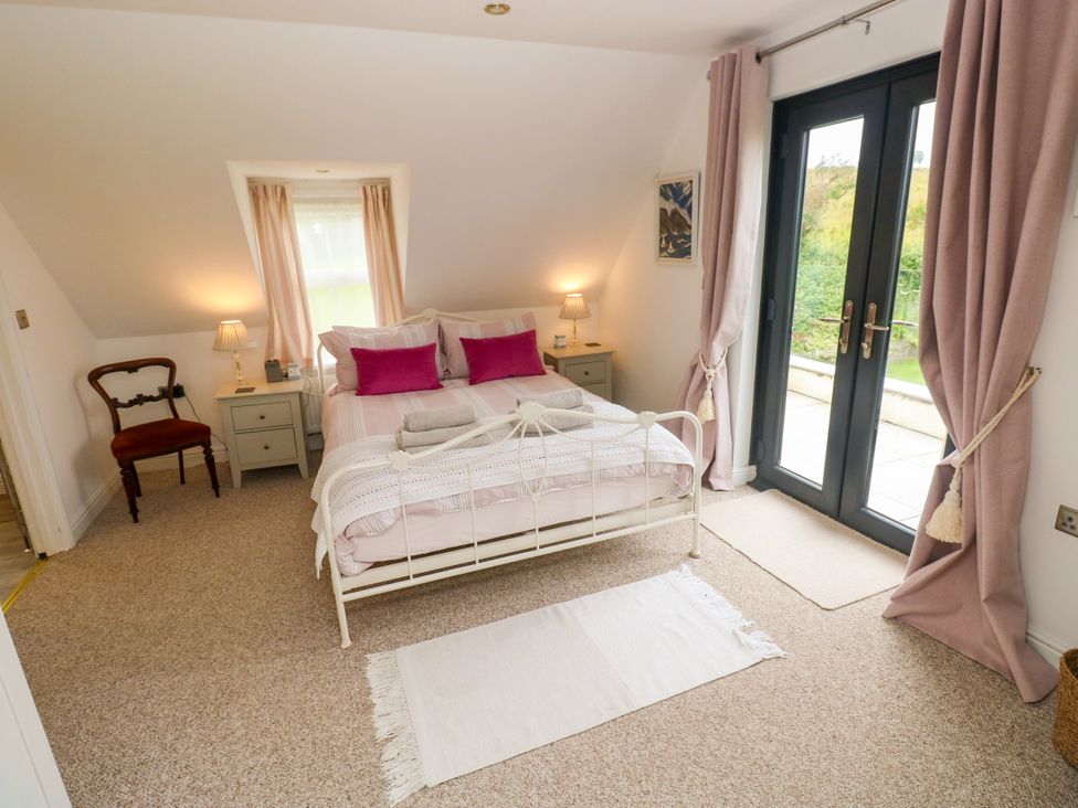 A bedroom with a bed and side tables at North Studdock Cottage in Angle near Pembroke