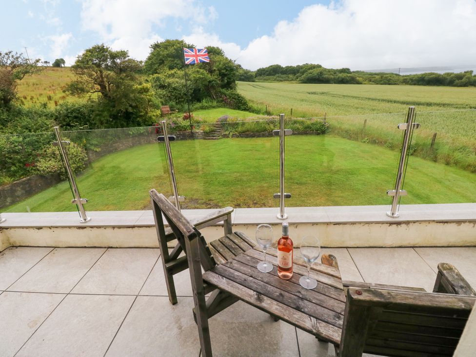 A patio with wine glasses and a garden view at North Studdock Cottage Angle near Pembroke