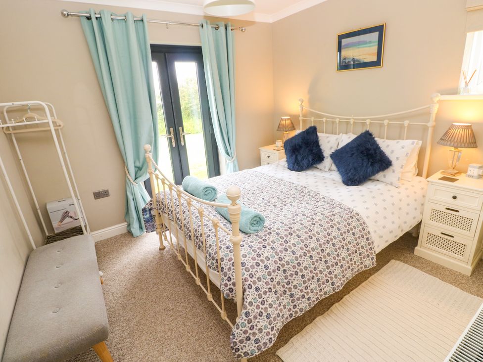 A bedroom with a bed and dual doors leading outside at North Studdock Cottage Angle near Pembroke